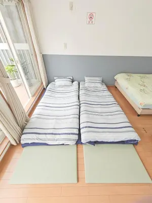 two beds in a room with mats on the floor at SunshineHouse \u5411\u5cf6 in Tokyo