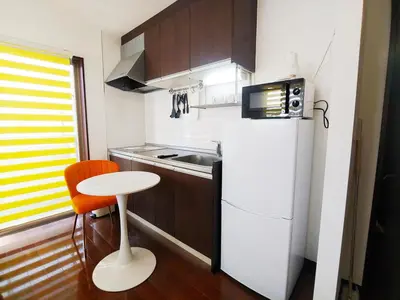 a small kitchen with a white refrigerator and a stool at MEZON DE OAK Shin-Okubo in Tokyo