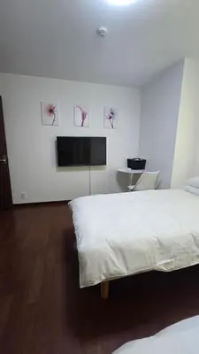 a bedroom with a bed and a flat screen tv at MEZON DE OAK Shin-Okubo in Tokyo