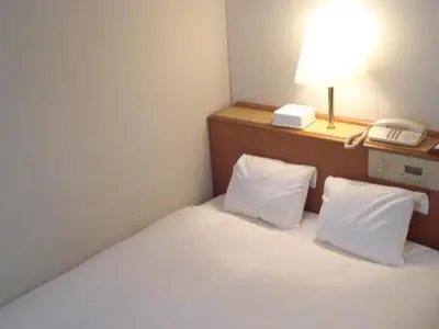 a hotel room with a bed with a phone and a lamp at Smile Hotel Sugamo in Tokyo