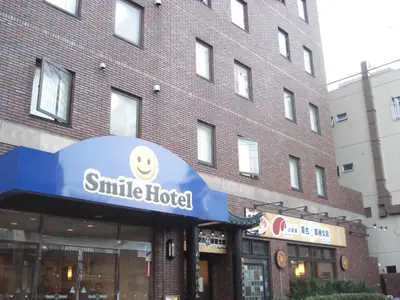 a smiley hotel sign in front of a brick building at Smile Hotel Sugamo in Tokyo