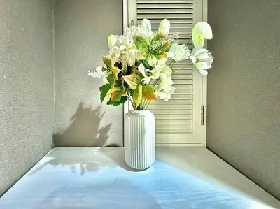 a white vase with white flowers in a window at Hokusai's House Shibuya Dogenzaka 311 in Tokyo