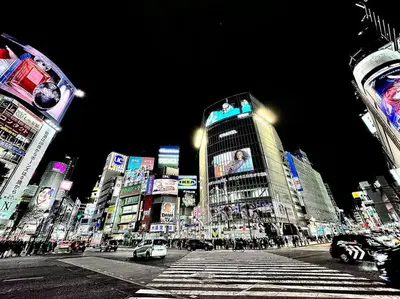 a busy city street at night with cars and buildings at Hokusai's House Shibuya Dogenzaka 311 in Tokyo