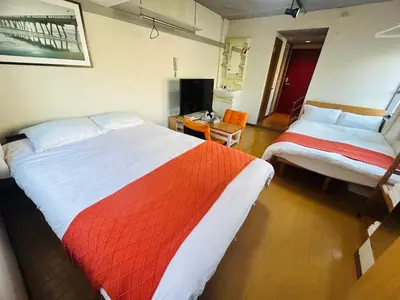 a hotel room with two beds and a television at Ueno Iriya Hotel in Tokyo