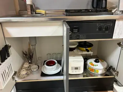 a kitchen cabinet filled with dishes and a microwave at Ueno Iriya Hotel in Tokyo