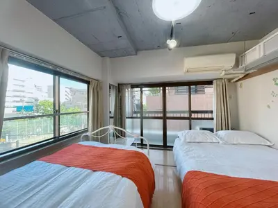 two beds in a room with a large window at Ueno Hotel Palazetto Iriya in Tokyo