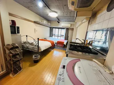 a small room with a bed and a room with a kitchen at Ueno Hotel Palazetto Iriya in Tokyo