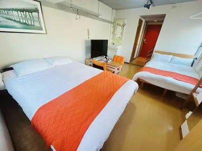 a bedroom with two beds with an orange and white blanket at Ueno Hotel Palazetto Iriya in Tokyo