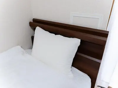 a bed with white sheets and a wooden headboard at Shin-Okubo Sta・1 min walk/　Shinjuku sta 2min/　Switch in Tokyo