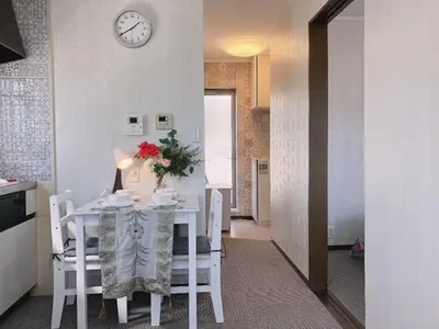 a kitchen with a table and chairs with a clock on the wall at Ikebukuro Florence Hostel in Tokyo