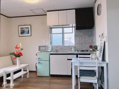 a kitchen with white cabinets and a blue refrigerator at Ikebukuro Florence Hostel in Tokyo