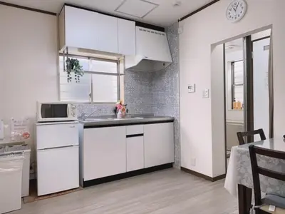 a kitchen with white cabinets and a counter top at Ikebukuro Florence Hostel in Tokyo