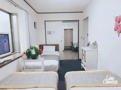 a hotel room with three beds and a tv at Ikebukuro Florence Hostel in Tokyo