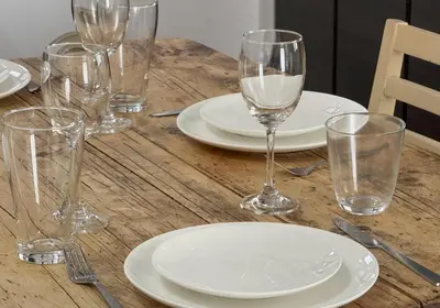 a wooden table with white plates and glasses on it at Good Space Hotel Yoyogi in Tokyo