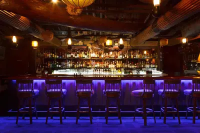 a bar with six bar stools in a room with purple lighting at Hotel New Otani Tokyo Garden Tower in Tokyo