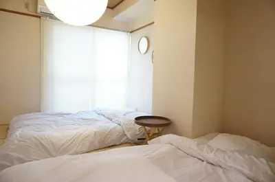 a bedroom with two beds and a clock on the wall at ALDO INN Kitasenju 3F in Tokyo