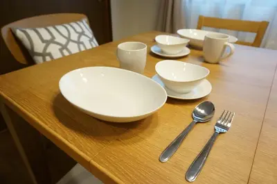 a wooden table with white bowls and utensils on it at ALDO INN Kitasenju 3F in Tokyo
