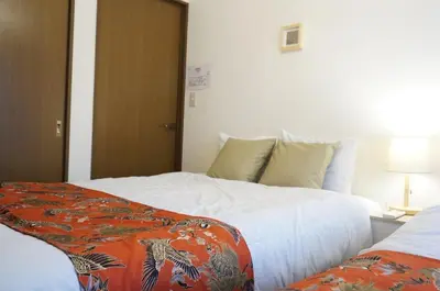 a hotel room with a bed with an orange blanket on it at ALDO INN Kitasenju 3F in Tokyo