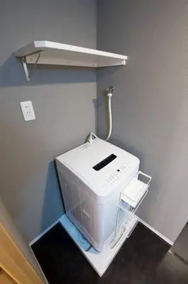 a white washing machine in a corner of a room at \u30b6\u30fb\u30b8\u30a7\u30df\u30cb\u30b9\u6c60\u888b101 in Tokyo