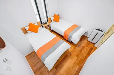 two beds in a room with white walls and wood floors at Ikebukuro Shopping Street 3BR in Tokyo