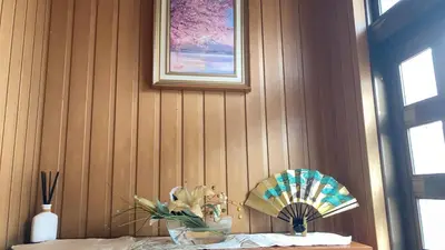 a wooden wall with a fan and a vase of flowers at Guesthouse cherry in Tokyo