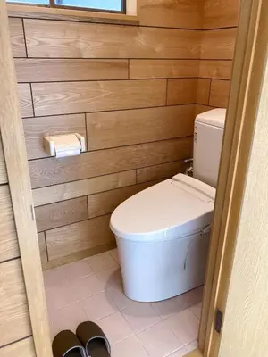 a bathroom with a toilet in a wooden wall at Guesthouse cherry in Tokyo