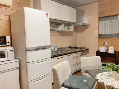 a kitchen with a white refrigerator and a glass table at Guesthouse cherry in Tokyo