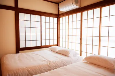 two beds in a room with large windows at 1stop to Shibuya station Japanese traditional house in Tokyo