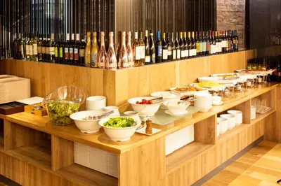 a buffet with bowls of food and bottles of wine at Hotel Mystays Gotanda Station in Tokyo