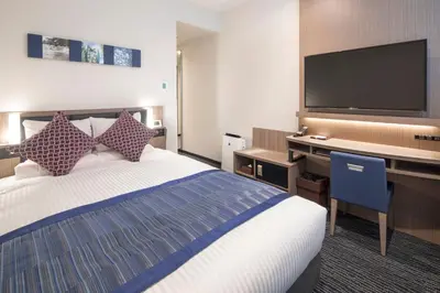 a hotel room with a bed and a desk with a flat screen tv at Hotel Mystays Gotanda Station in Tokyo