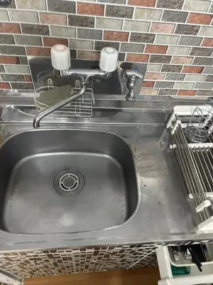 a stainless steel sink in a kitchen with a brick wall at Local Stay NAKAI in Tokyo