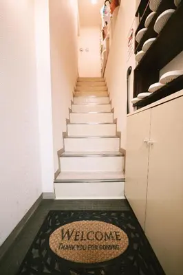 a hallway with stairs with a welcome rug on the floor at Akasaka Central Hostel Roppongi Akasaka in Tokyo