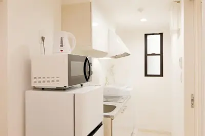 a white kitchen with a microwave on top of a refrigerator at Mi-HOTEL CALM RIVERSIDE in Tokyo