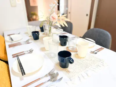 a table with white plates and utensils on it at Shinkoiwa Stay, Private House, Nearby Station, Good access to Ueno&Asakusa in Tokyo