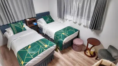 a small room with two beds and a chair at Sunflower \u6c11\u6cca in Tokyo