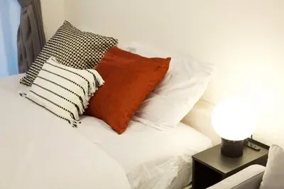 a white bed with pillows and a table with a lamp at \u30bb\u30f3\u30c8\u30ec\u30a4\u62bc\u4e0a\u30ce\u30fc\u30b9 205 in Tokyo