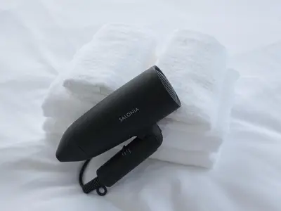 a black hair dryer next to a pile of towels at Hatagaya heim 403 in Tokyo
