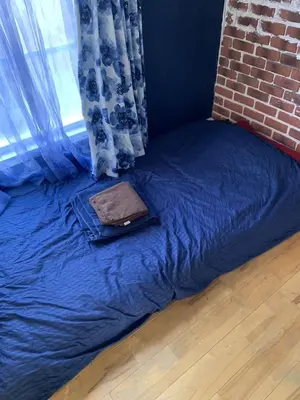 a bed with a bag on it next to a brick wall at The Standard Apartment SHIBUYA SASAZUKA Room K in Tokyo