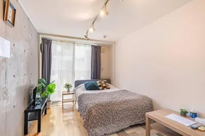 a bedroom with a bed and a desk and a window at Shirokane Apartment Hotel 2 in Tokyo