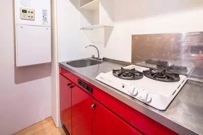 a kitchen with red cabinets and a white stove top oven at Shirokane Apartment Hotel 2 in Tokyo