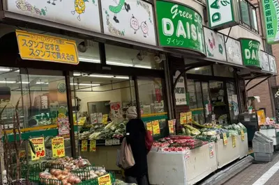 a woman is standing in front of a grocery store at Shirokane Apartment Hotel 2 in Tokyo