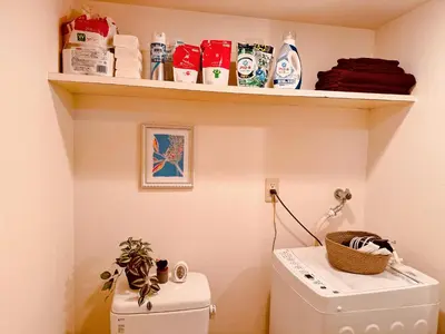 a bathroom with a shelf above a washing machine at Shirokane Apartment Hotel 2 in Tokyo