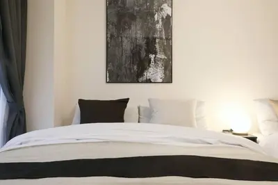 a bedroom with a white bed with a painting on the wall at \u30b5\u30f3\u30cf\u30a4\u30c4\u521d\u53f0 201 in Tokyo