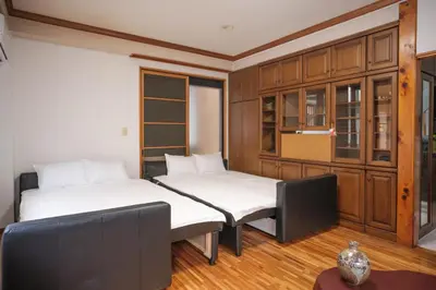 two beds in a room with wooden cabinets at Miyabi Inn-Kameido in Tokyo