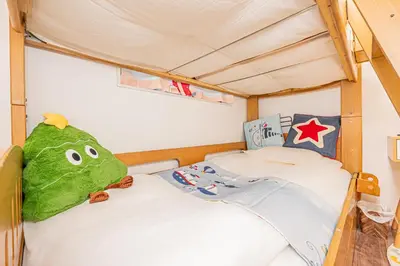 a bedroom with a green stuffed frog sitting on a bed at jr\u99c54\u5206\u65b0\u7bc992\u5e73\u7c73\u8eca\u5eab\u4ed8\u4e00\u6238\u5efa\u548c\u98a8\u5bdd\u5ba4\u5e83\u3044\u30ea\u30d3\u30f3\u30b0\u4e0a\u91ce\u79cb\u8449\u539f\u6771\u4eac\u54c1\u5ddd\u76f4\u901a in Tokyo