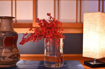 a vase with red flowers in it next to a lamp at ICHINAGI Yanaka Luxury Villa near Asakusa in Tokyo