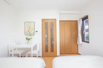 a bedroom with two beds and a table and a door at walk to Ushigome-yanagicho sta. EoWh in Tokyo