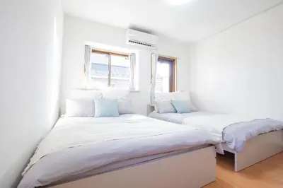 two beds in a white room with two windows at walk to Ushigome-yanagicho sta. EoWh in Tokyo