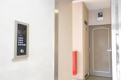 a hallway with a door and a red fire extinguisher at walk to Ushigome-yanagicho sta. EoWh in Tokyo