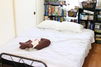 a large white bed in a room with bookshelves at \u30dc\u30fc\u30c9\u30b2\u30fc\u30e0\u304c\u697d\u3057\u3081\u308b\u65b0\u5bbf\u99c5\u5f92\u6b69\u570f\u5185\u306e\u8cb8\u5207\u30a2\u30d1\u30fc\u30c8 in Tokyo